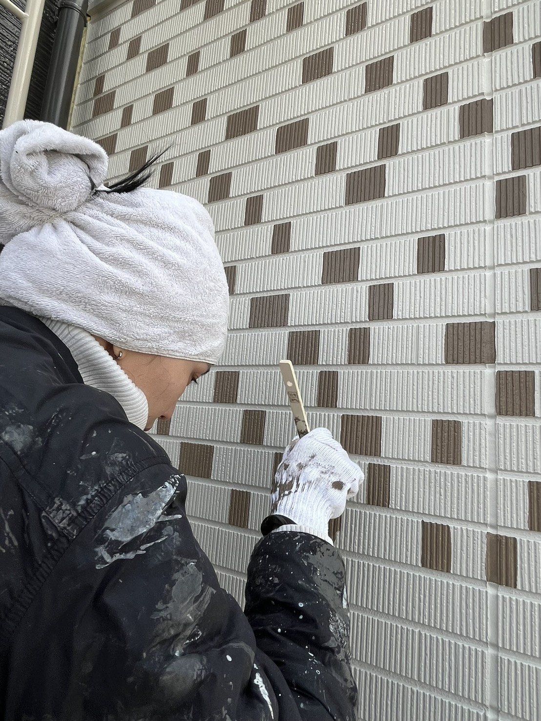 職人が外壁の目地を塗っている